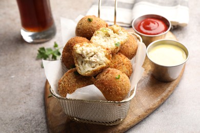 Photo of Delicious fried croquette balls and sauces on grey textured table, closeup