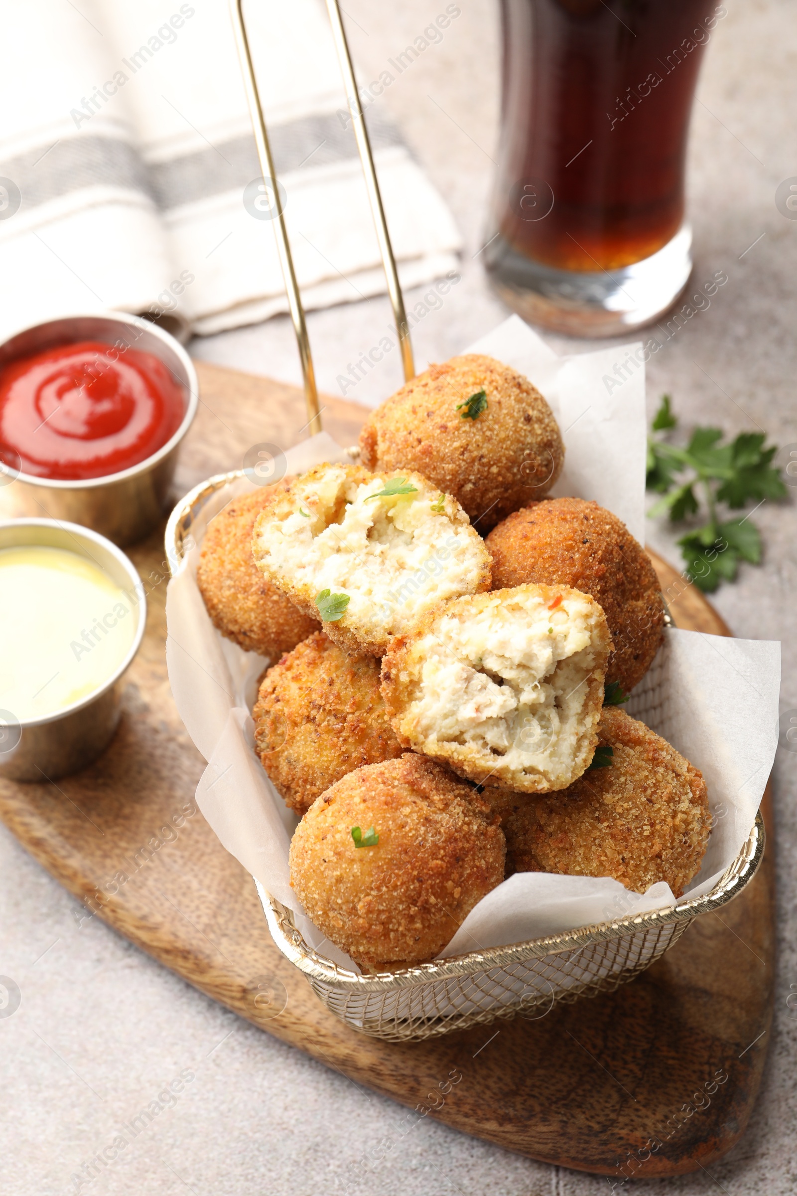 Photo of Delicious fried croquette balls and sauces on grey textured table, closeup