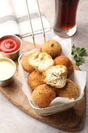 Photo of Delicious fried croquette balls and sauces on grey textured table, closeup
