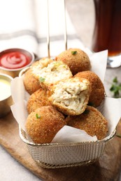 Photo of Delicious fried croquette balls and sauces on grey textured table, closeup