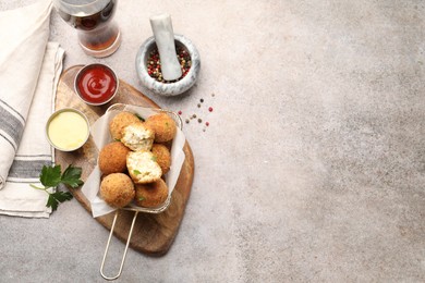 Photo of Delicious fried croquette balls with parsley, sauces and spices on grey textured table, flat lay. Space for text