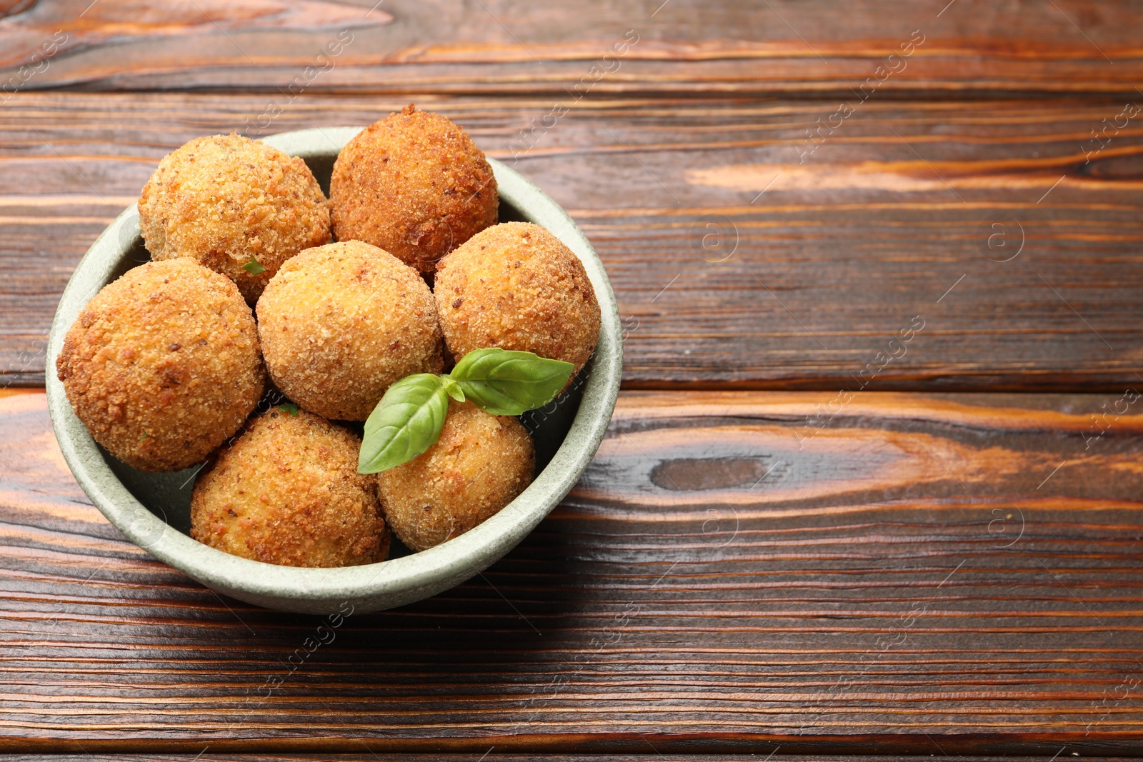 Delicious fried croquette balls with basil in bowl on wooden table, closeup. Space for text Photo of Delicious fried croquette balls with basil in bowl on wooden table, closeup. Space for text