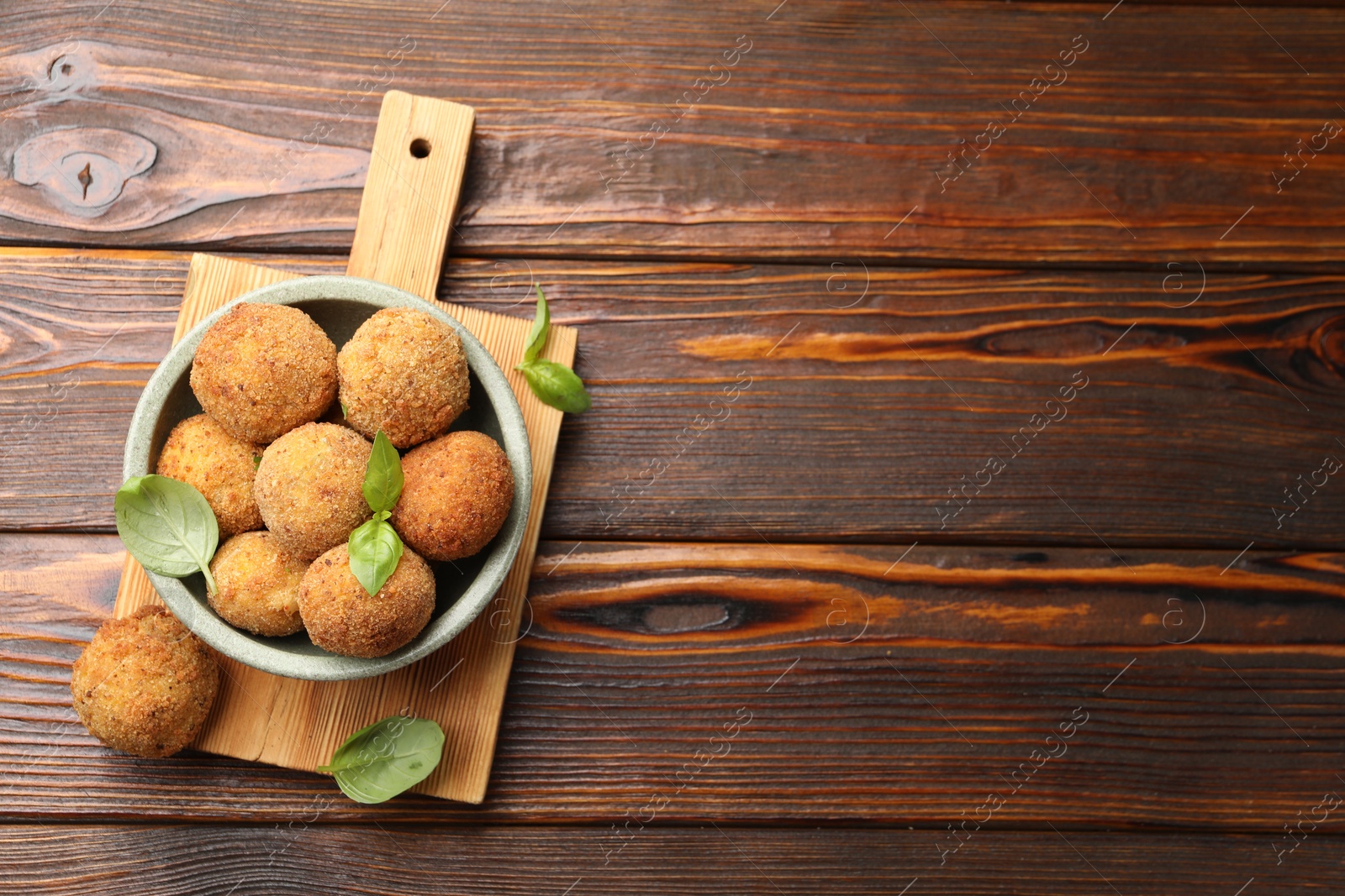 Delicious fried croquette balls with basil in bowl on wooden table, top view. Space for text Photo of Delicious fried croquette balls with basil in bowl on wooden table, top view. Space for text