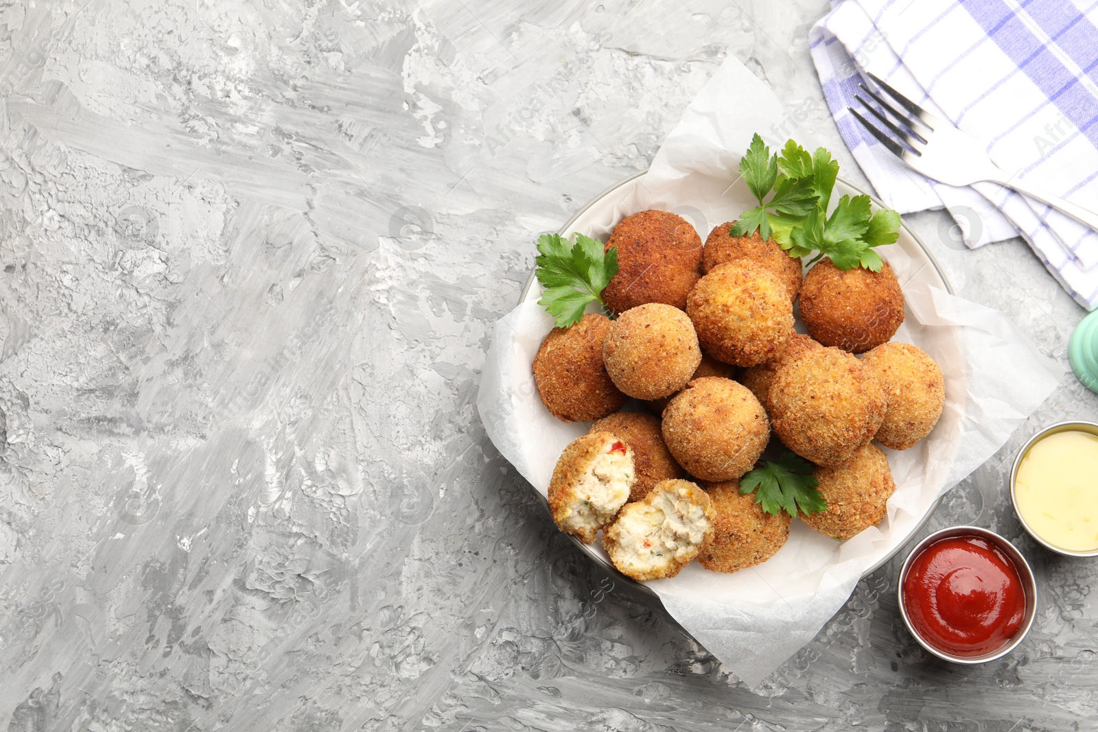 Delicious fried croquette balls with parsley and sauces on grey textured table, flat lay. Space for text Photo of Delicious fried croquette balls with parsley and sauces on grey textured table, flat lay. Space for text