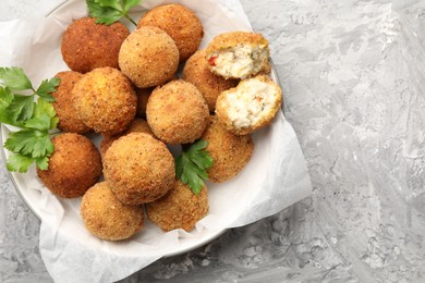 Photo of Delicious fried croquette balls with parsley on grey textured table, top view