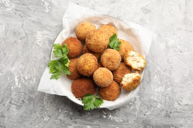 Photo of Delicious fried croquette balls with parsley on grey textured table, top view
