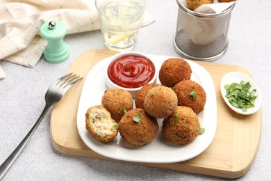 Photo of Delicious fried croquette balls with parsley and ketchup on grey textured table, closeup
