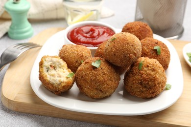 Photo of Delicious fried croquette balls with parsley and ketchup on grey textured table, closeup