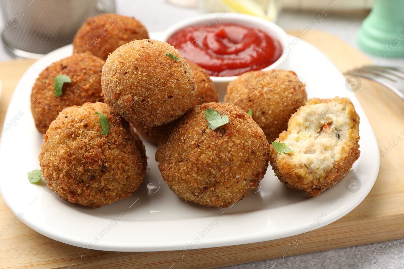 Photo of Delicious fried croquette balls with parsley and ketchup on grey textured table, closeup