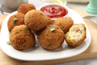 Photo of Delicious fried croquette balls with parsley and ketchup on grey textured table, closeup