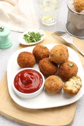 Photo of Delicious fried croquette balls with parsley and ketchup on grey textured table, closeup