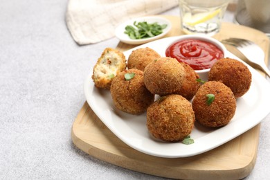 Photo of Delicious fried croquette balls with parsley and ketchup on grey textured table, closeup
