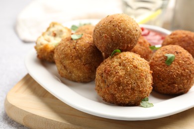 Photo of Delicious fried croquette balls with parsley and ketchup on grey textured table, closeup