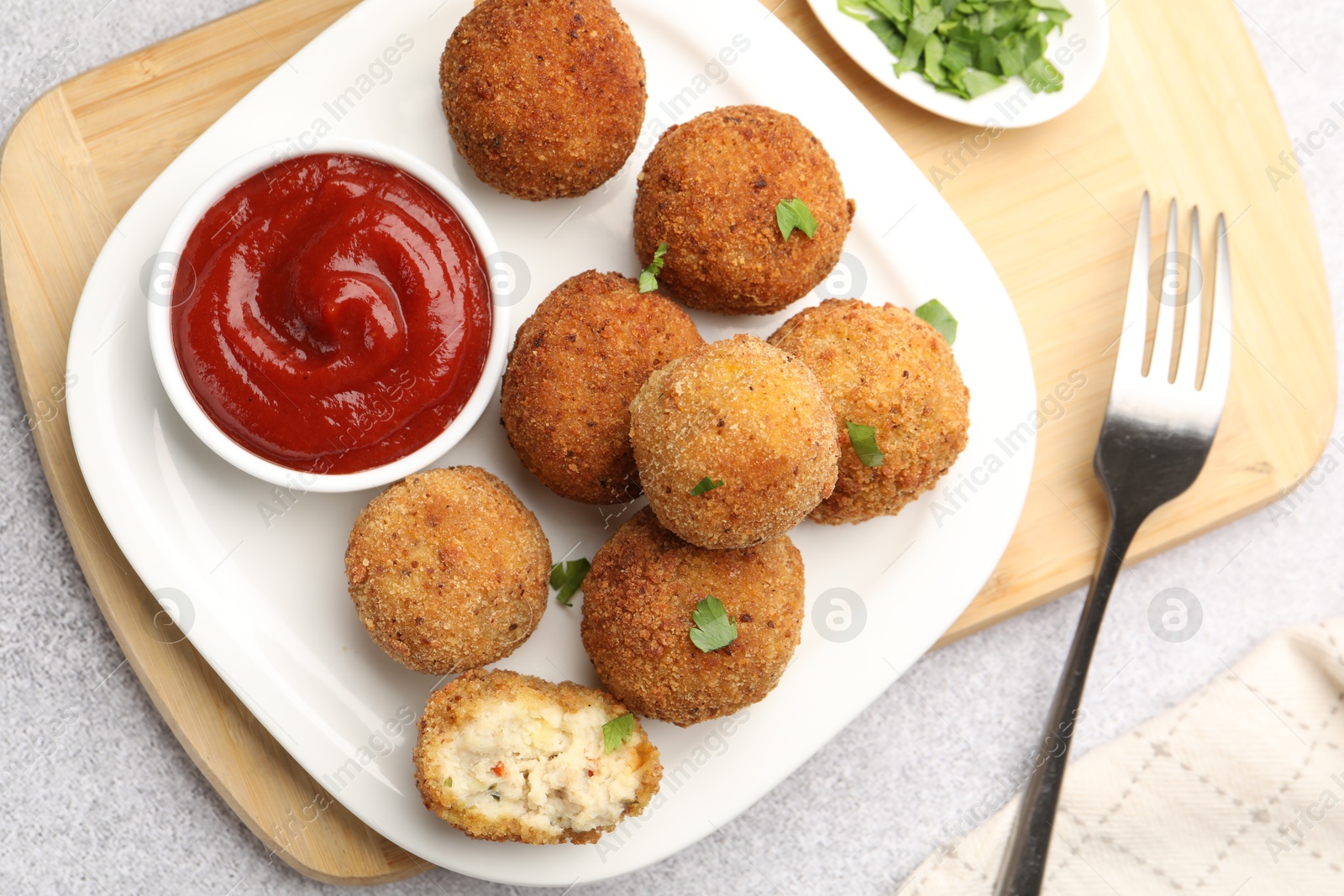 Delicious fried croquette balls with parsley and ketchup served on grey textured table, flat lay Photo of Delicious fried croquette balls with parsley and ketchup served on grey textured table, flat lay