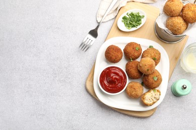 Photo of Delicious fried croquette balls with parsley and ketchup served on grey textured table, flat lay. Space for text