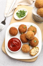 Photo of Delicious fried croquette balls with parsley and ketchup served on grey textured table, flat lay