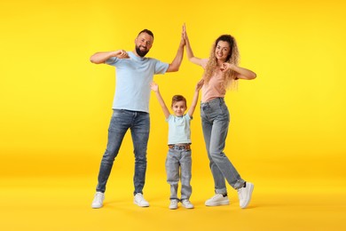 Photo of Happy family. Parents giving high five and their son on yellow background