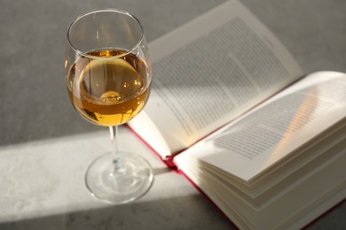 Photo of Glass of wine and book on grey table
