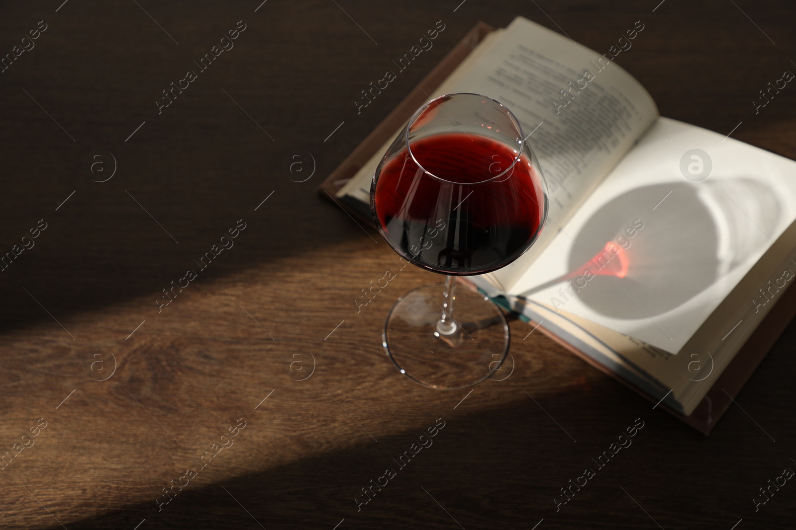 Glass of wine and book on wooden table. Space for text Photo of Glass of wine and book on wooden table. Space for text
