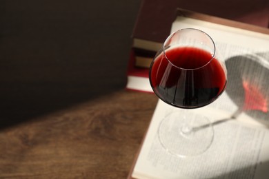 Photo of Glass of wine and books on wooden table. Space for text