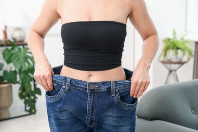 Photo of Fit woman wearing old jeans after weight loss at home, closeup