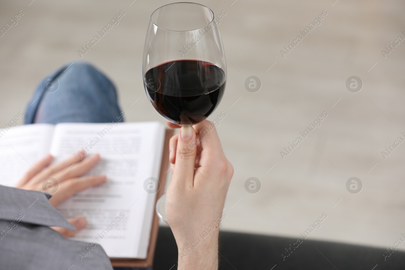Woman with glass of wine reading book on sofa at home, closeup. Space for text Photo of Woman with glass of wine reading book on sofa at home, closeup. Space for text