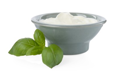 Photo of Tasty yoghurt in bowl and basil isolated on white