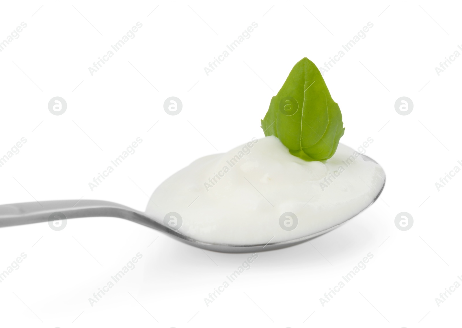 Tasty yoghurt with basil in spoon isolated on white Photo of Tasty yoghurt with basil in spoon isolated on white