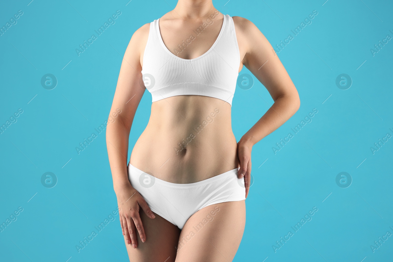 Woman in underwear on light blue background, closeup Photo of Woman in underwear on light blue background, closeup