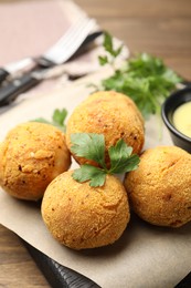 Photo of Delicious fried croquette balls with parsley on wooden table, closeup
