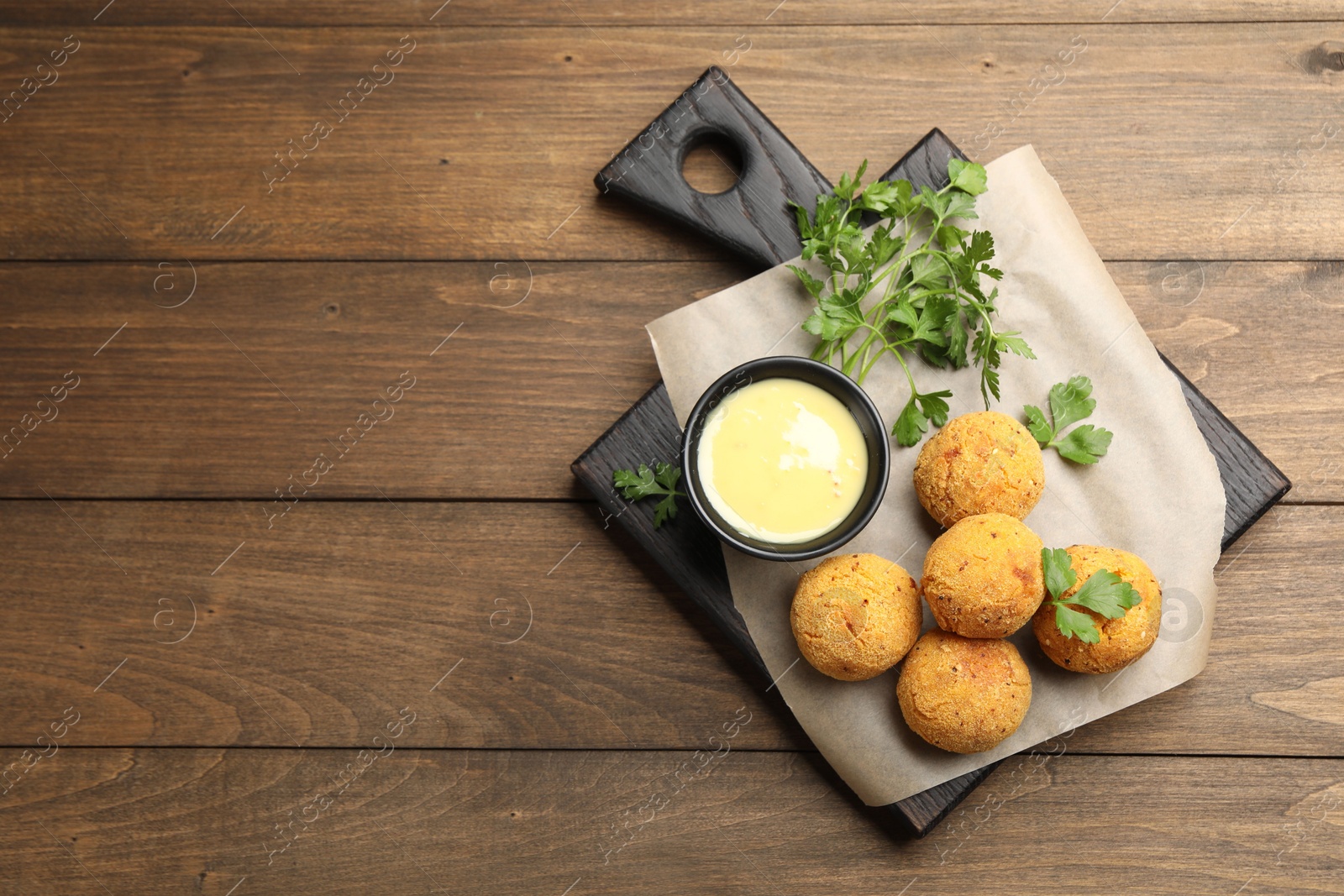 Delicious fried croquette balls with parsley and sauce on wooden table, top view. Space for text Photo of Delicious fried croquette balls with parsley and sauce on wooden table, top view. Space for text