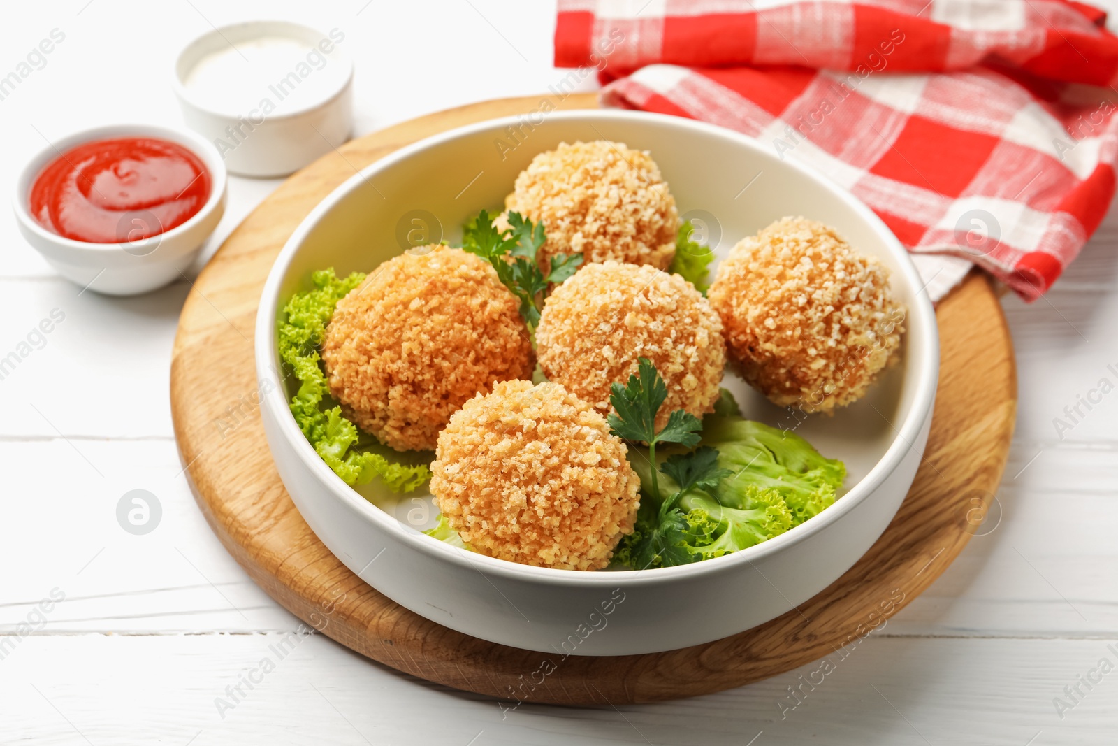 Photo of Delicious fried croquette balls with parsley and lettuce on white wooden table, closeup