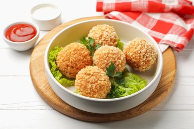 Photo of Delicious fried croquette balls with parsley and lettuce on white wooden table, closeup