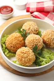 Photo of Delicious fried croquette balls with parsley and lettuce on white wooden table, closeup