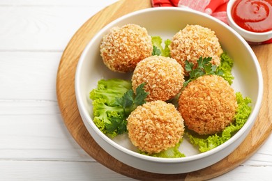 Photo of Delicious fried croquette balls with parsley and lettuce on white wooden table, closeup