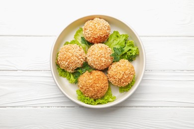 Photo of Delicious fried croquette balls with parsley and lettuce on white wooden table, top view