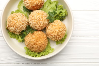 Photo of Delicious fried croquette balls with parsley and lettuce on white wooden table, top view