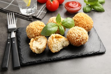 Photo of Delicious fried croquette balls with basil on grey table, closeup