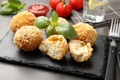 Photo of Delicious fried croquette balls with basil on grey table, closeup
