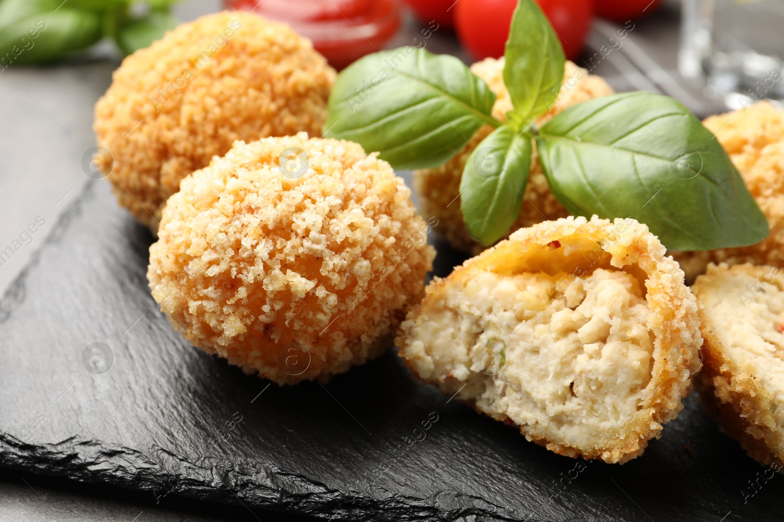 Photo of Delicious fried croquette balls with basil on grey table, closeup