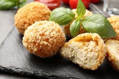 Photo of Delicious fried croquette balls with basil on grey table, closeup