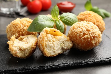 Photo of Delicious fried croquette balls with basil on grey table, closeup