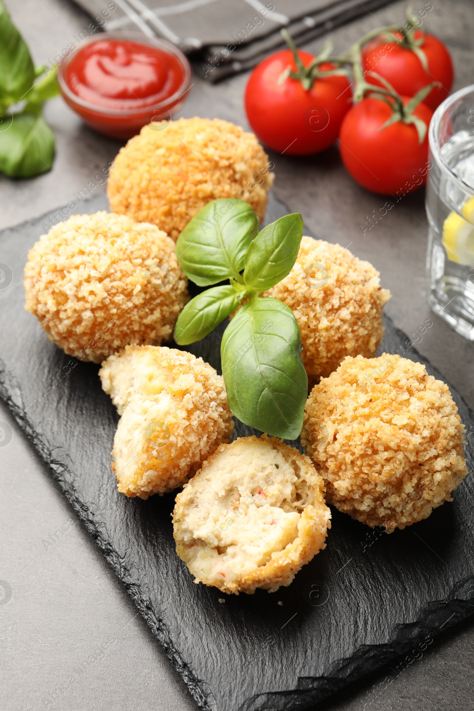 Delicious fried croquette balls with basil on grey table, closeup Photo of Delicious fried croquette balls with basil on grey table, closeup