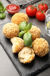 Photo of Delicious fried croquette balls with basil on grey table, closeup