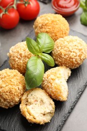 Photo of Delicious fried croquette balls with basil on grey table, closeup