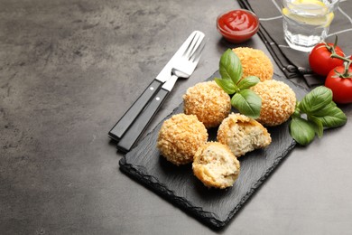 Photo of Delicious fried croquette balls with basil on grey textured table, closeup. Space for text