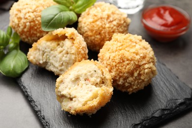 Photo of Delicious fried croquette balls with basil on grey table, closeup