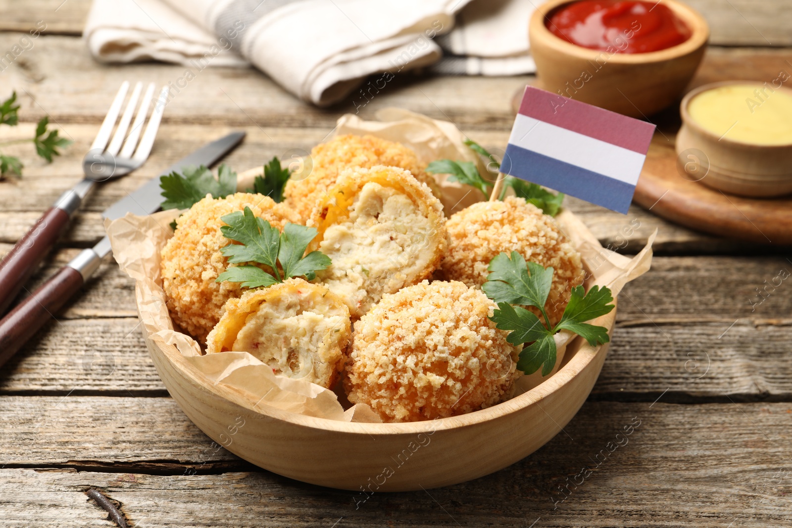 Delicious fried croquette balls, parsley and small flag of Netherlands on wooden table, closeup Photo of Delicious fried croquette balls, parsley and small flag of Netherlands on wooden table, closeup