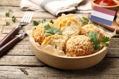 Photo of Delicious fried croquette balls, parsley and small flag of Netherlands on wooden table, closeup