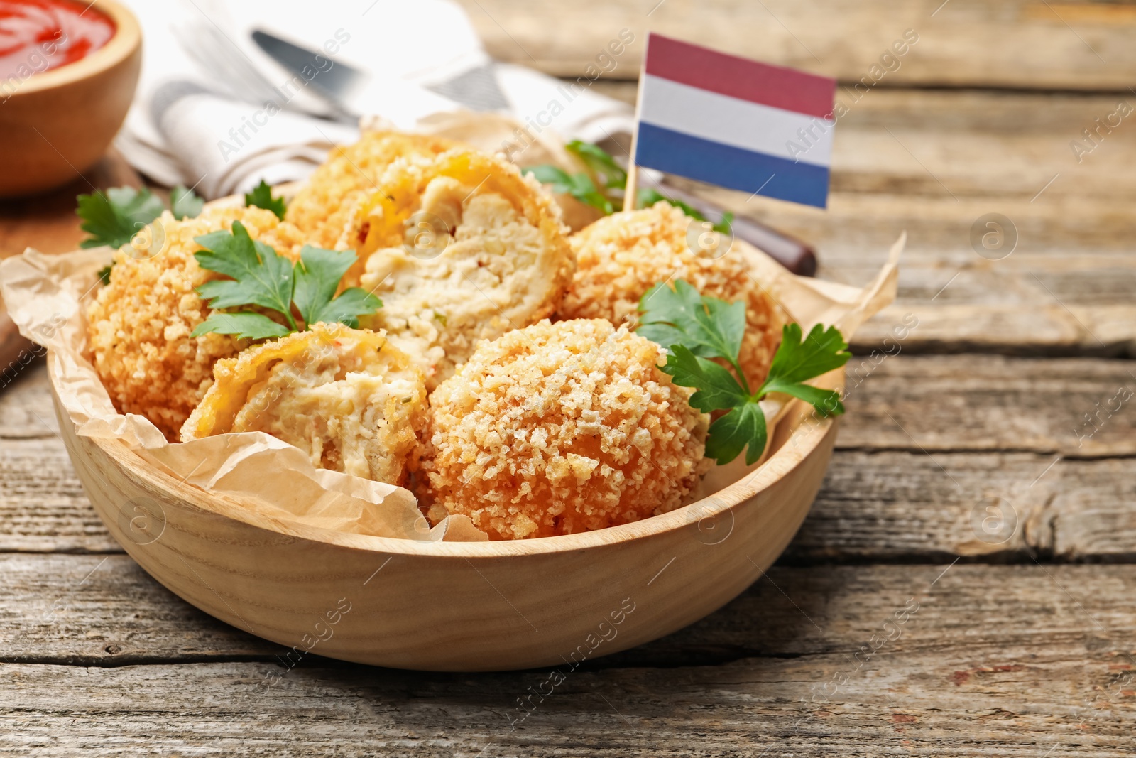 Delicious fried croquette balls, parsley and small flag of Netherlands on wooden table, closeup Photo of Delicious fried croquette balls, parsley and small flag of Netherlands on wooden table, closeup